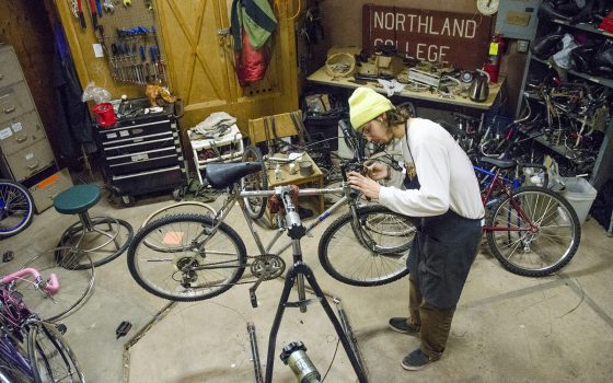 Northland College student working on bike.