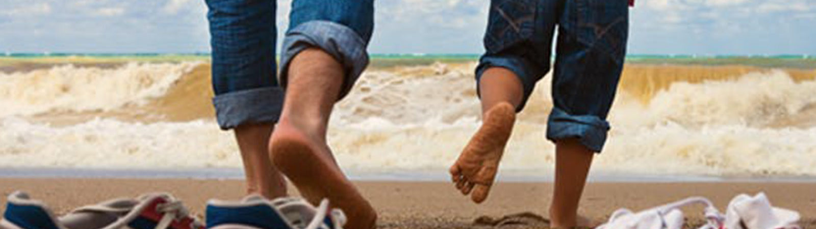 Family running into the waves with their shoes on the beach