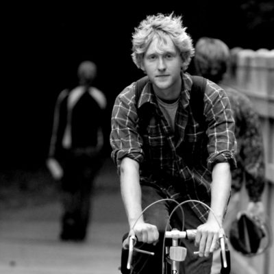 Black and white photo of student biking on bridge