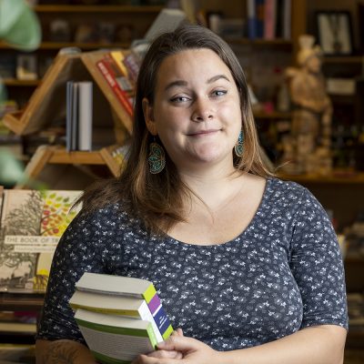 Northland College alum Halee Kirkwood holds books inside bookstore.