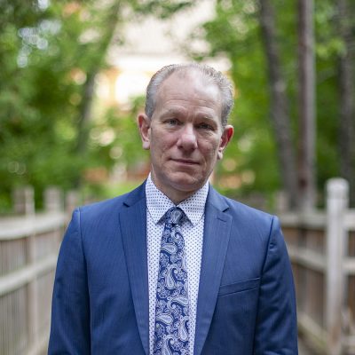 President Karl Solibakke stands on a bridge in a blue blazer and tie.