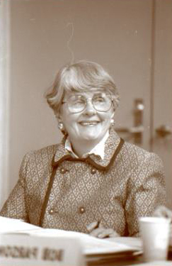 Board of Trustees Chair May Van Evera sits at a board table.