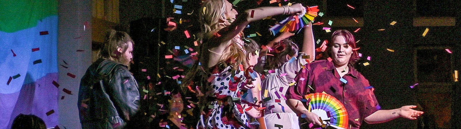 Students performing drag with confetti in the air in Baldwin Commons