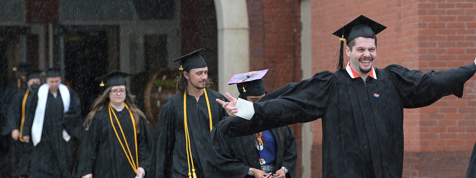 Students in graduation caps and gowns process toward the site of their Commencement Ceremony