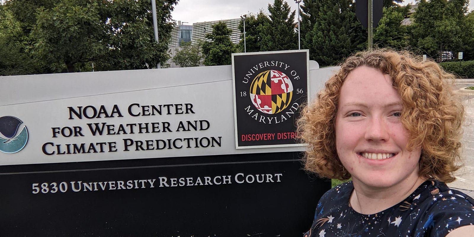 Brianna Hauke ’24 stands in front of a sign for the NOAA Center for Weather and Climate Prediction