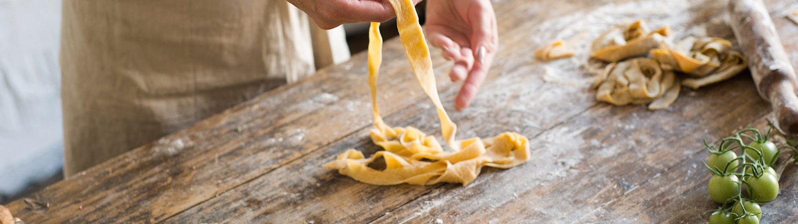 A person wearing an apron makes pasta from scratch