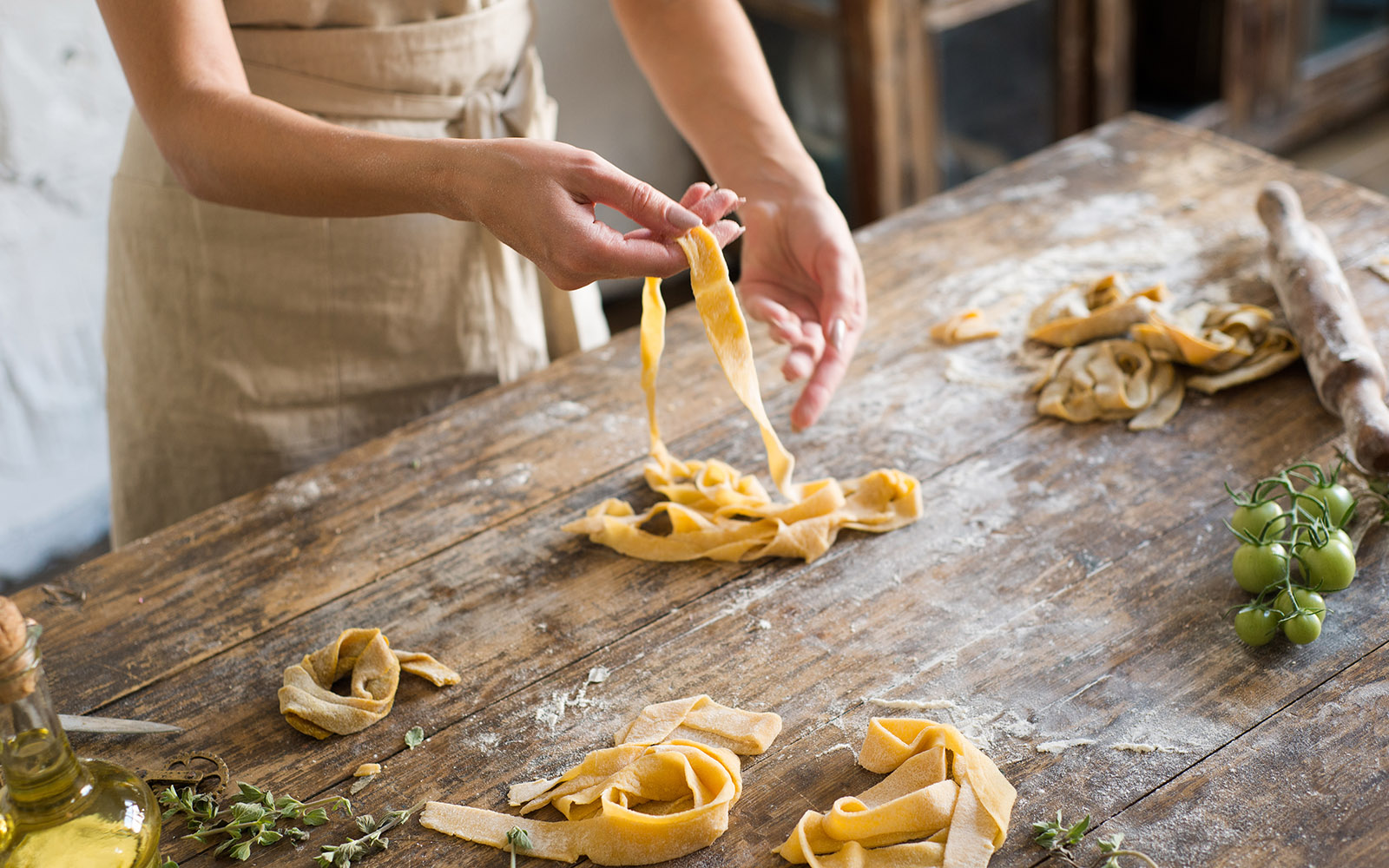 A person wearing an apron makes pasta from scratch