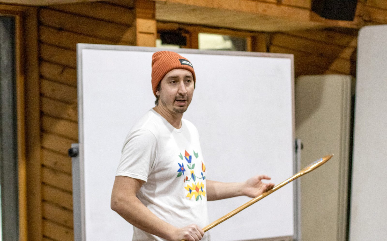 Dylan Bizhikiins Jennings giving a talk with a snow snake